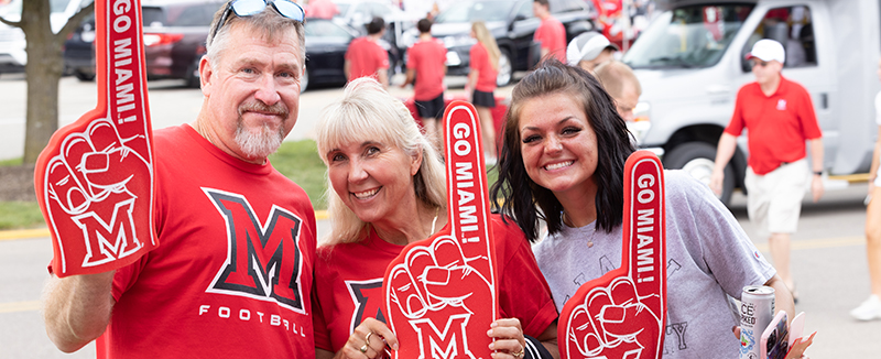 image of a dad, mom, and daughter holding Miami gear